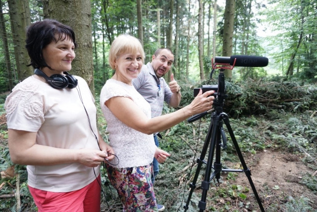 a filmteam around a camera on a tripod in a forest