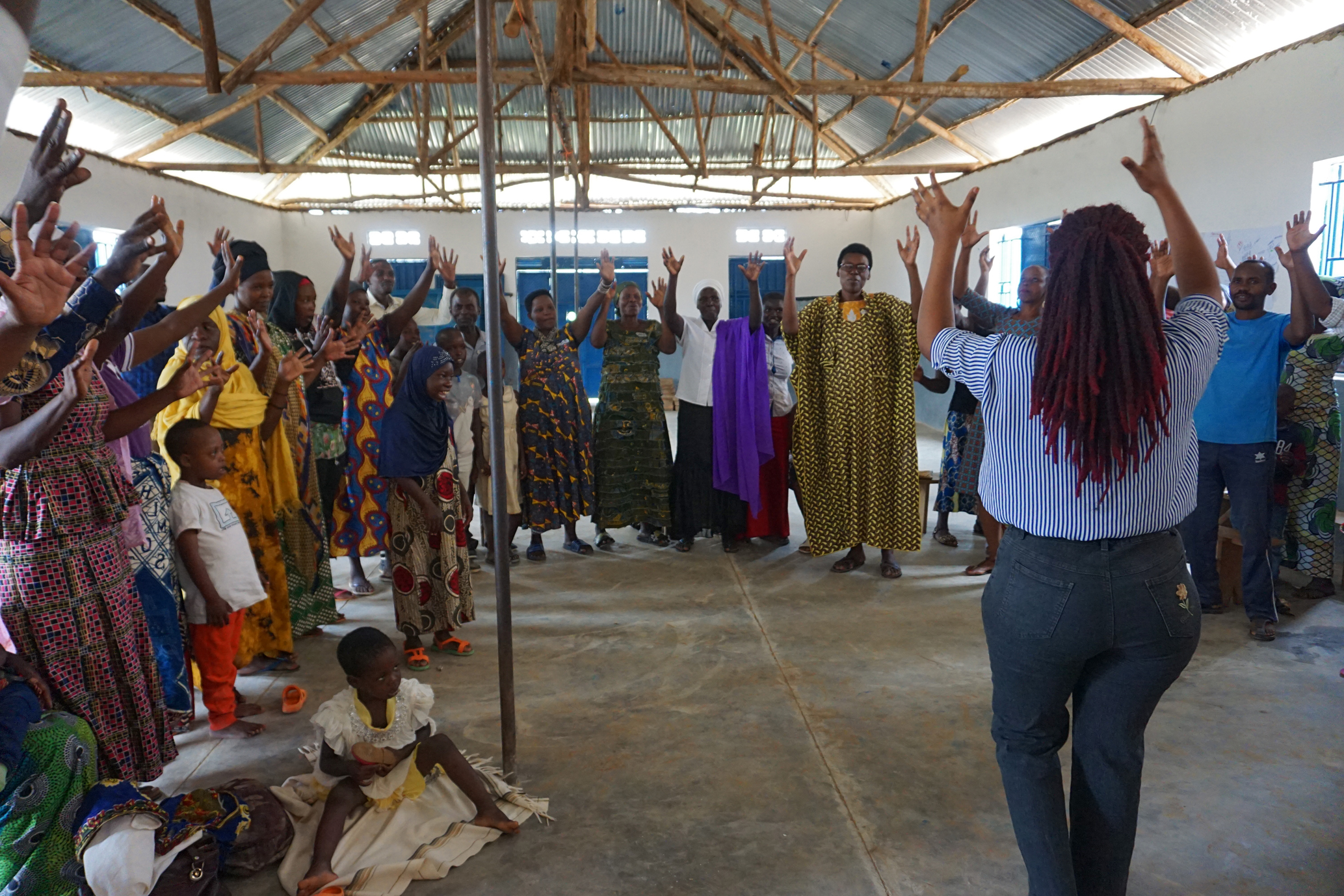a facilitator animates a group of people who all have their hands in the air