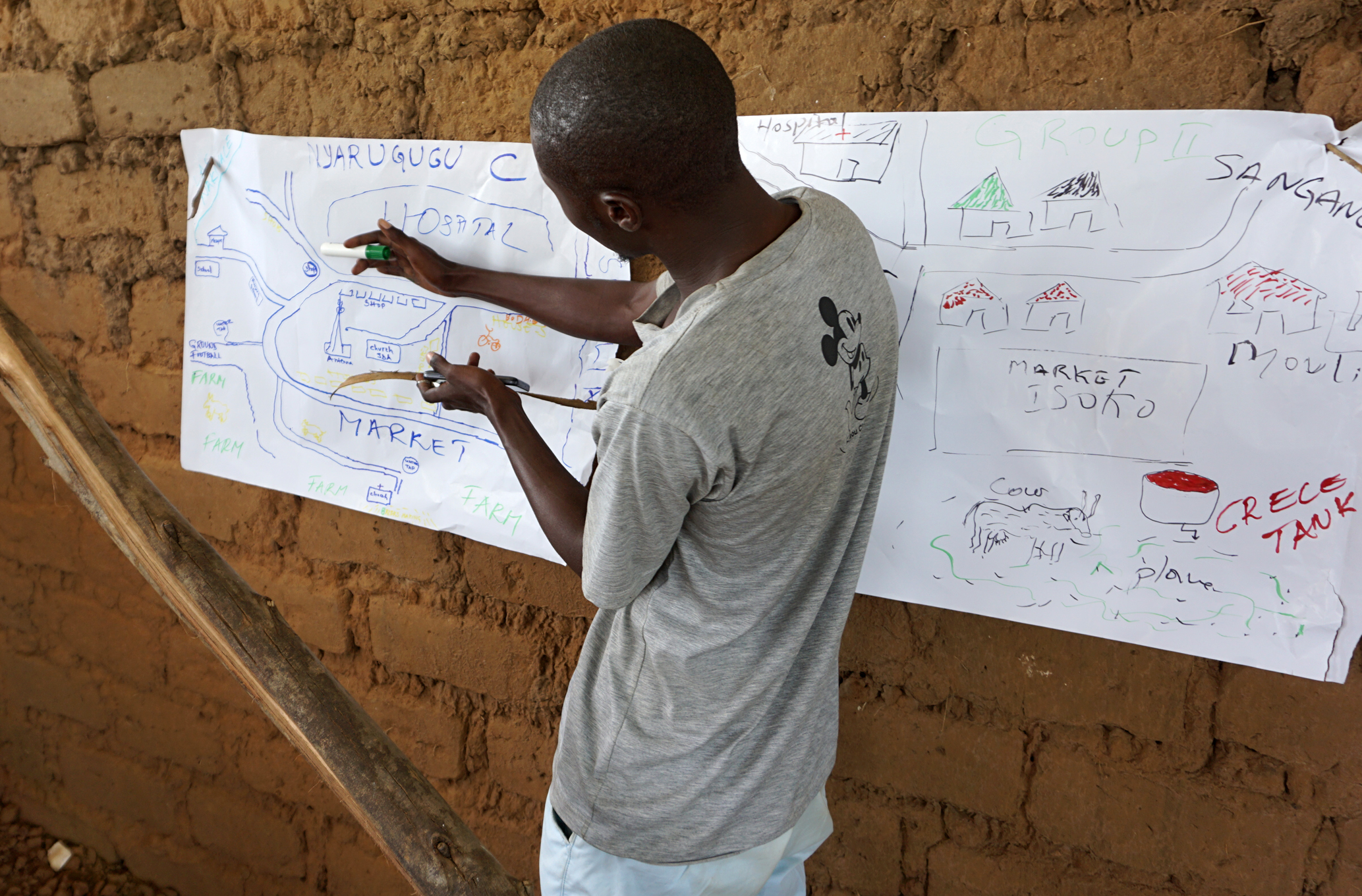 A man stands in front of a flip chart with a drawing of a map of his community