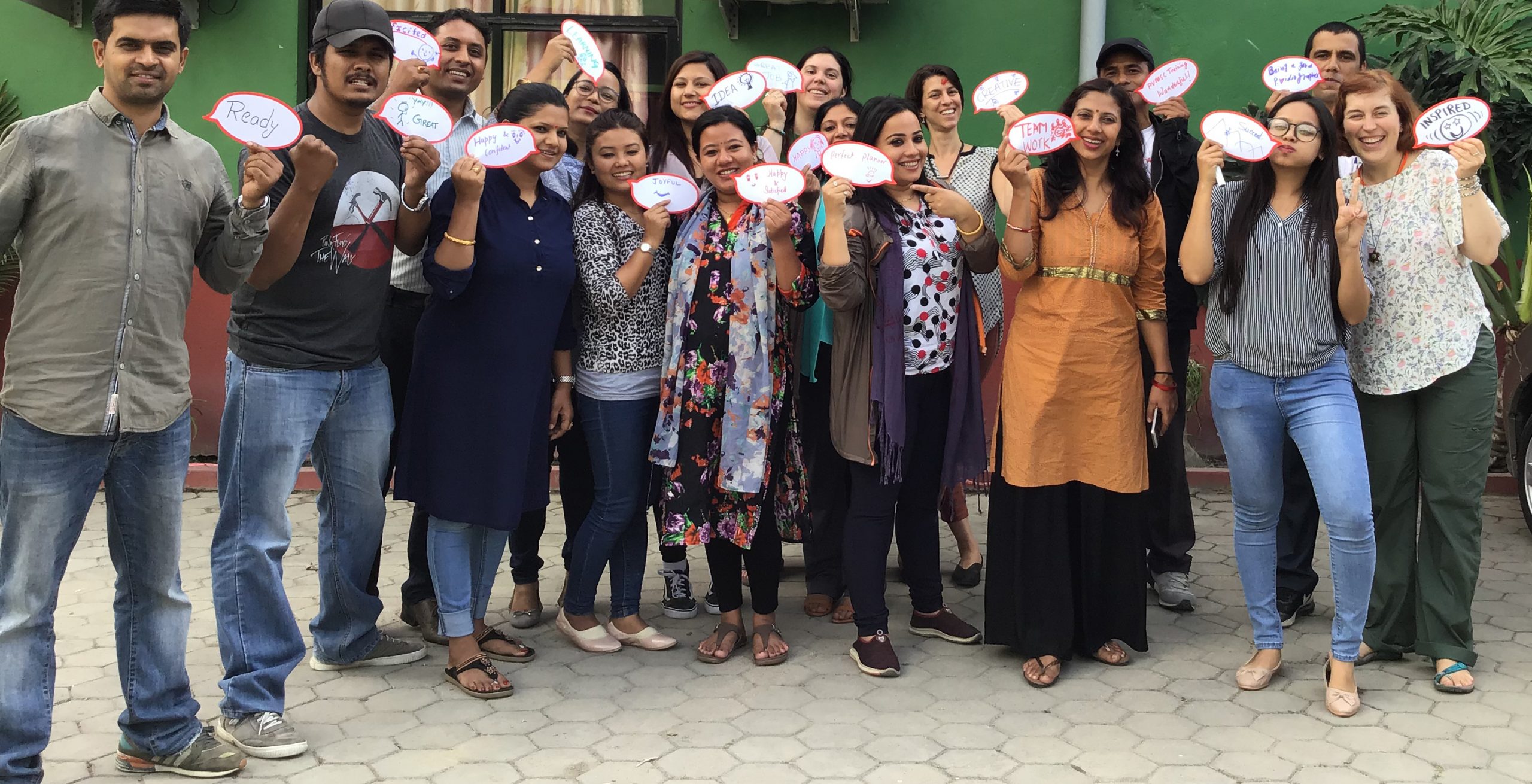 a group of trainees posing with speech bubble papers signifying the successful completion of the workshop